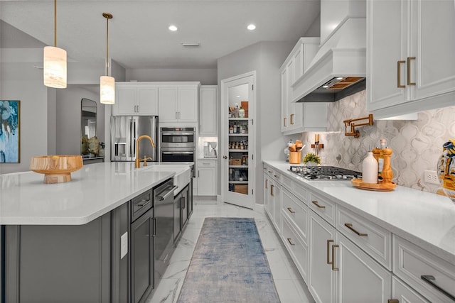 13319 Deep Blue Pl, Bradenton, FL 34211 - kitchen with custom exhaust hood, appliances with stainless steel finishes, white cabinets, backsplash, and light countertops