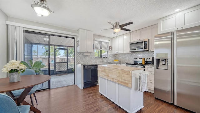 kitchen with decorative backsplash, a center island, white cabinets, dark wood finished floors, and appliances with stainless steel finishes