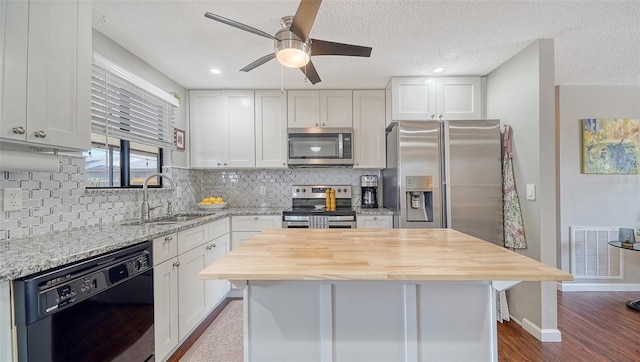 kitchen with ceiling fan, visible vents, appliances with stainless steel finishes, a sink, and wood counters