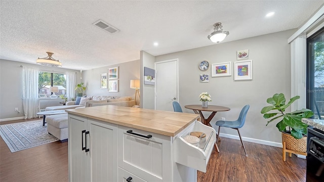 kitchen with visible vents, dark wood-style flooring, wooden counters, baseboards, and a textured ceiling