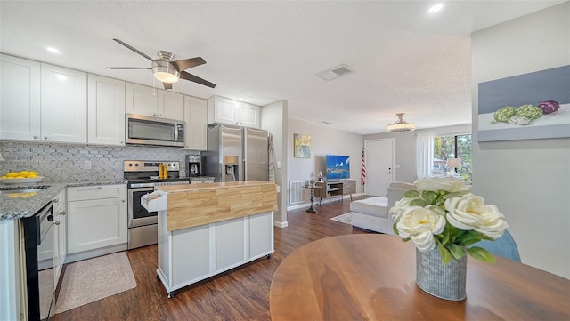 kitchen featuring appliances with stainless steel finishes, wooden counters, decorative backsplash, dark wood-type flooring, and visible vents