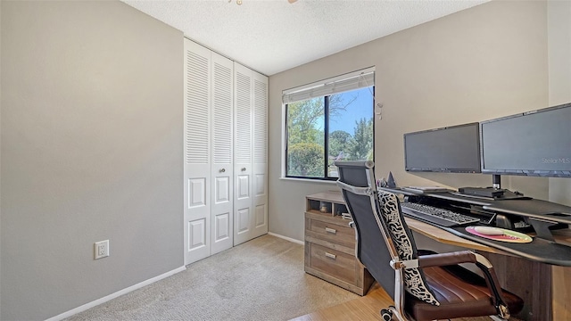 office featuring baseboards, light carpet, and a textured ceiling