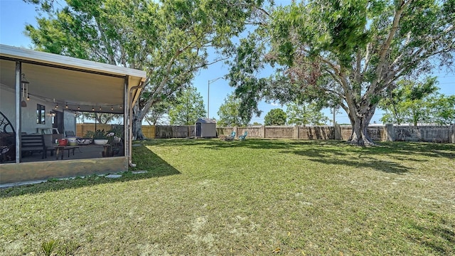 view of yard with a fenced backyard, an outdoor structure, a patio, and a storage shed