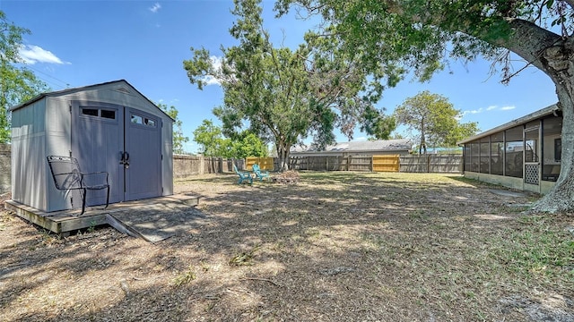 view of yard with a sunroom, a fenced backyard, a storage unit, and an outdoor structure