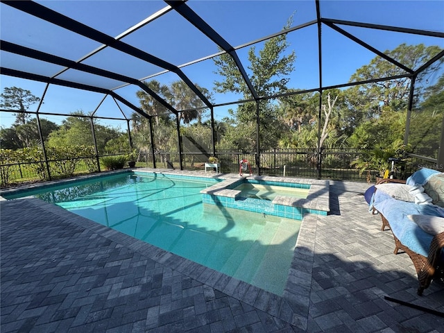 view of pool featuring a lanai, a pool with connected hot tub, and a patio area