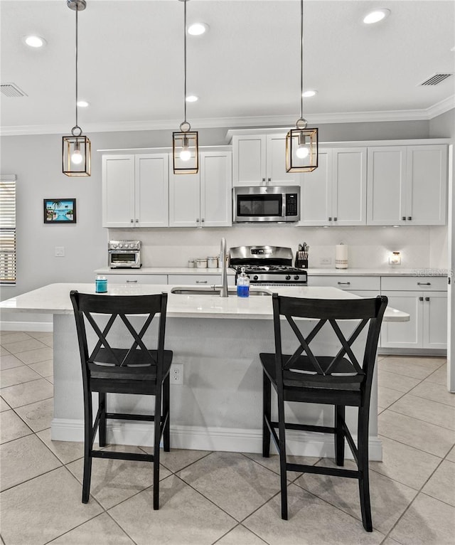 kitchen with crown molding, a breakfast bar area, visible vents, and stainless steel appliances