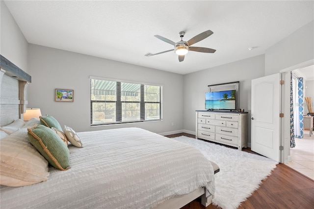 bedroom featuring wood finished floors, a ceiling fan, and baseboards