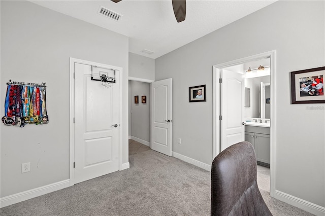 interior space with light carpet, ceiling fan, a sink, baseboards, and visible vents