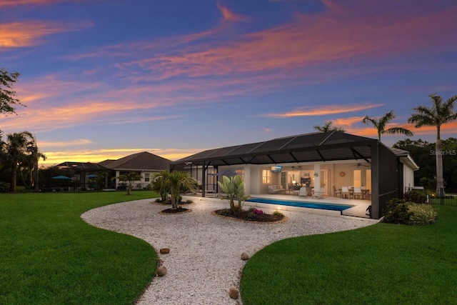 14210 9th Ter NE, Bradenton, FL 34212 - back of house at dusk with a ceiling fan, a lawn, a patio area, and an outdoor pool