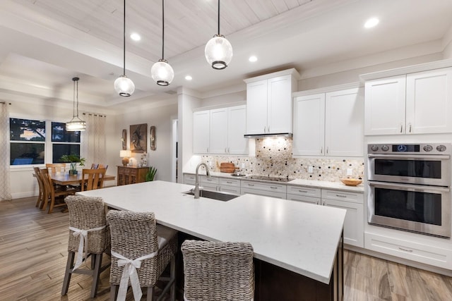 14210 9th Ter NE, Bradenton, FL 34212 - kitchen featuring a sink, stainless steel double oven, black electric cooktop, a kitchen island with sink, and backsplash