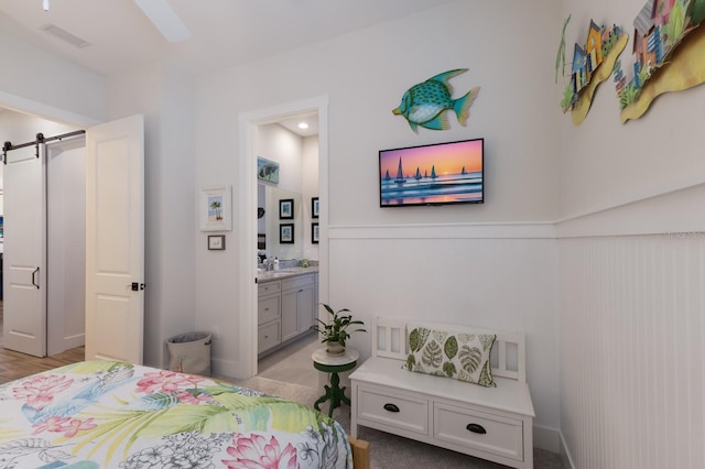 14210 9th Ter NE, Bradenton, FL 34212 - bedroom featuring a barn door, wainscoting, connected bathroom, and a sink