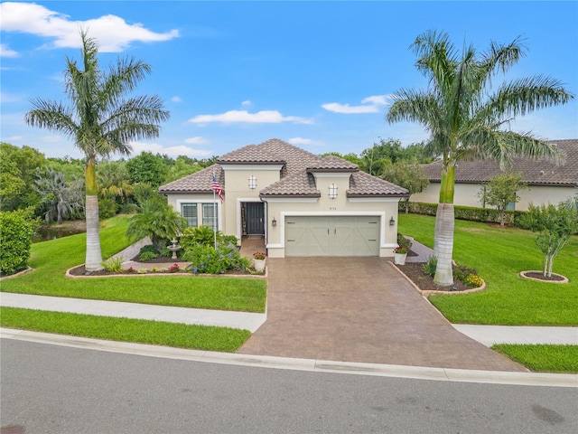 mediterranean / spanish home with a tiled roof, driveway, a front lawn, an attached garage, and stucco siding