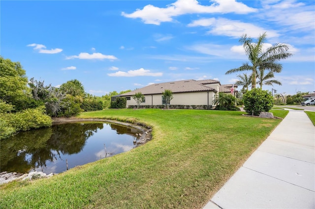 view of side of home featuring a lawn, a water view, and stucco siding
