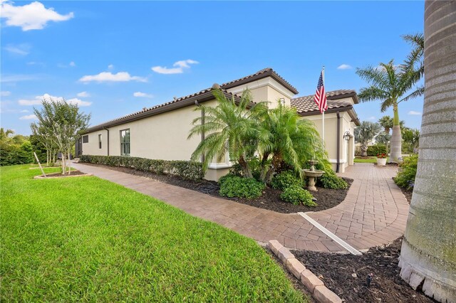 view of home's exterior with a lawn, stucco siding, and a tiled roof