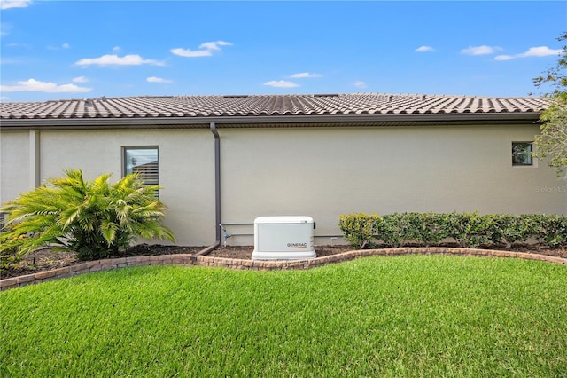 view of home's exterior with a lawn, stucco siding, and a tile roof