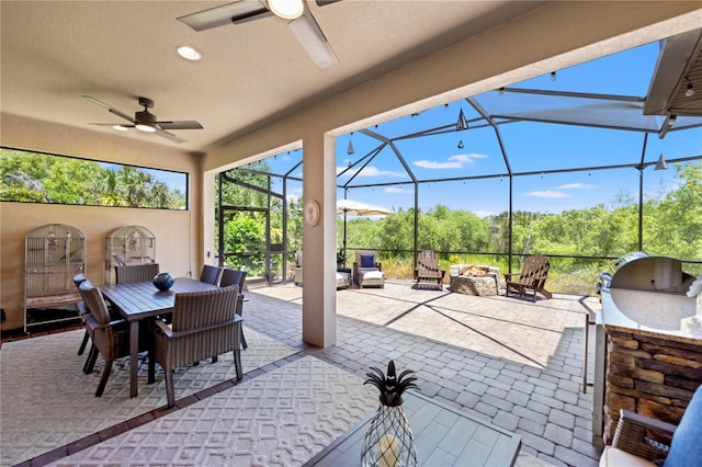 view of patio / terrace featuring ceiling fan, a lanai, an outdoor fire pit, an outdoor kitchen, and outdoor dining space