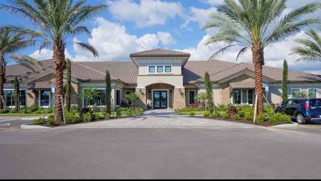 mediterranean / spanish-style house featuring french doors, stucco siding, and a tiled roof