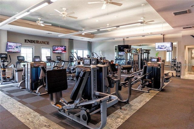 exercise room featuring a ceiling fan, a tray ceiling, and visible vents
