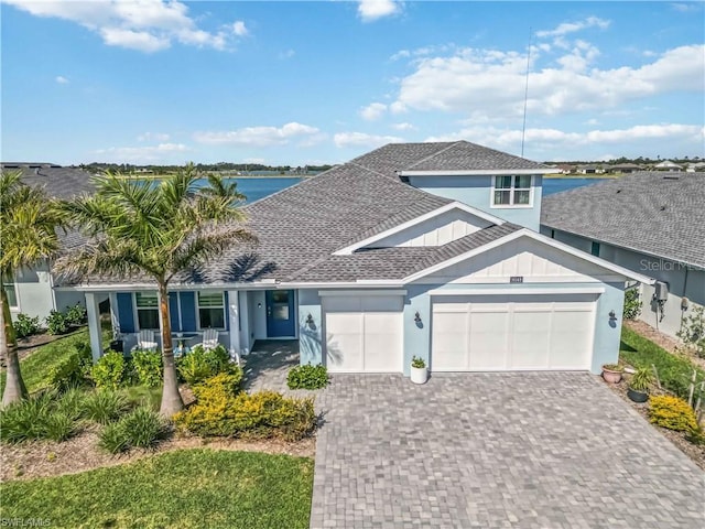 view of front of house featuring board and batten siding, a shingled roof, a water view, driveway, and an attached garage