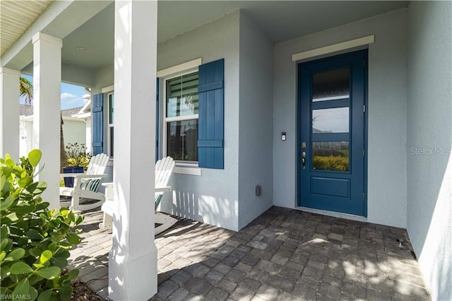entrance to property featuring a porch and stucco siding