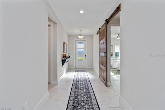 hall with baseboards, a barn door, light tile patterned floors, and recessed lighting