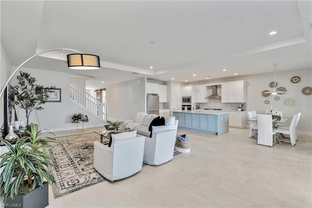 living room with stairway, recessed lighting, a tray ceiling, and baseboards