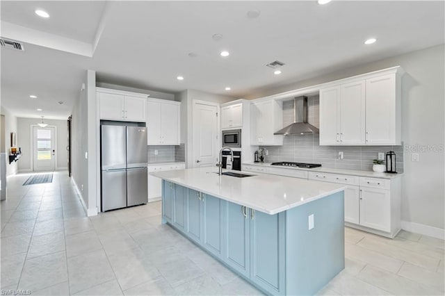 kitchen featuring wall chimney range hood, visible vents, stainless steel appliances, and white cabinetry