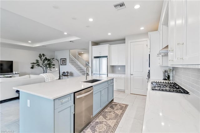 kitchen featuring appliances with stainless steel finishes, open floor plan, white cabinetry, and a sink