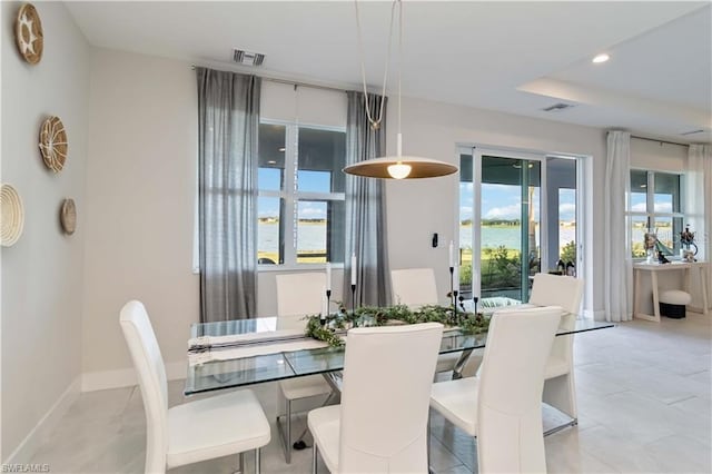 dining space featuring baseboards, visible vents, a water view, and recessed lighting