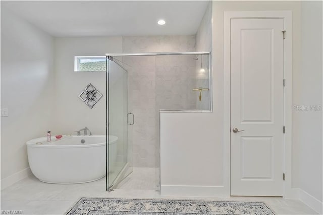 full bathroom featuring baseboards, a freestanding tub, and a shower stall