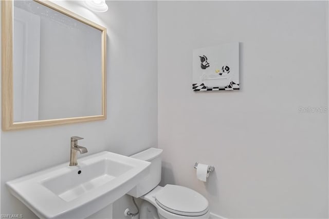 bathroom with toilet, a sink, and baseboards