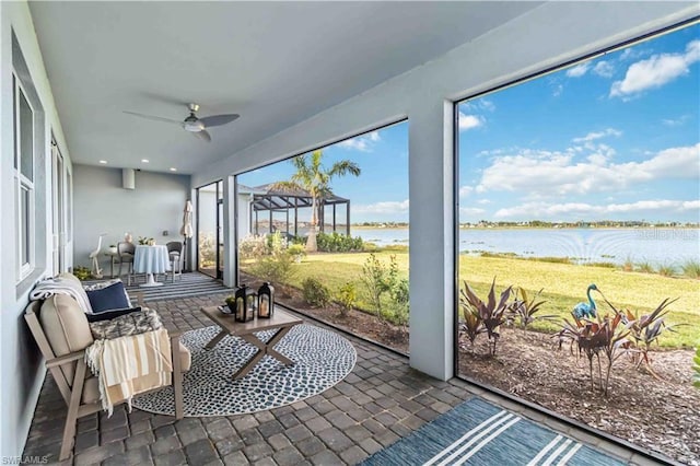 sunroom / solarium with ceiling fan and a water view