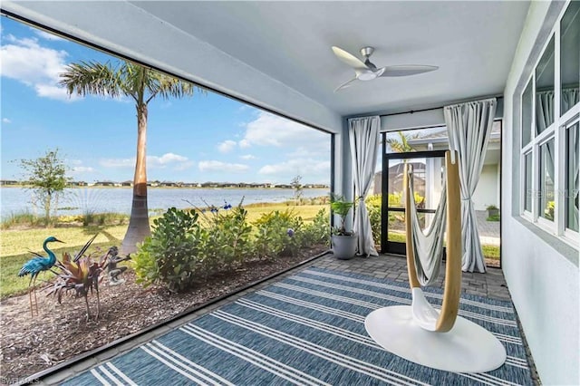 unfurnished sunroom featuring a ceiling fan and a water view