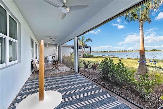sunroom / solarium featuring a ceiling fan and a water view