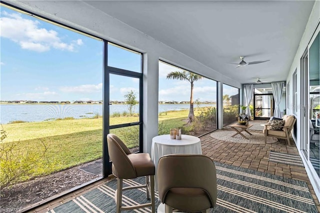 sunroom / solarium featuring ceiling fan and a water view