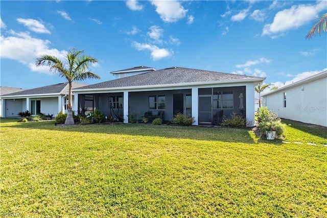 rear view of house featuring a lawn and a sunroom