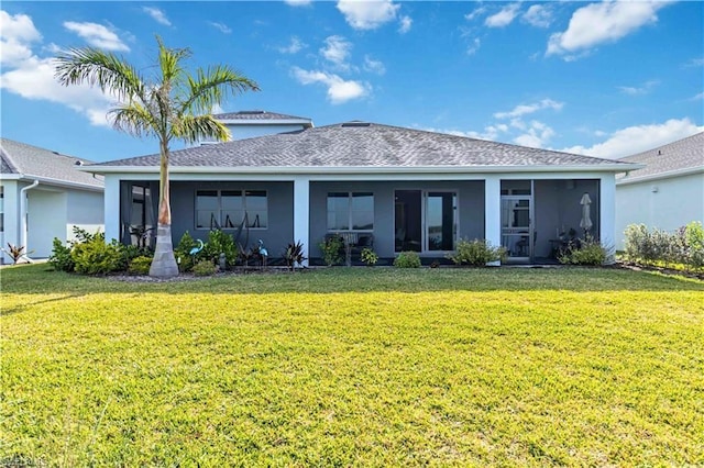 rear view of property featuring roof with shingles, stucco siding, a yard, and a sunroom