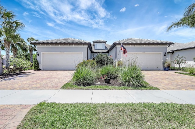 12291 Myrtle Bay Ct, Sarasota, FL 34238 - mediterranean / spanish house featuring stucco siding, decorative driveway, an attached garage, and a tile roof