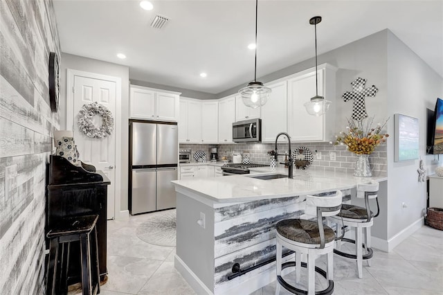 12291 Myrtle Bay Ct, Sarasota, FL 34238 - kitchen with appliances with stainless steel finishes, a peninsula, white cabinets, a breakfast bar, and backsplash
