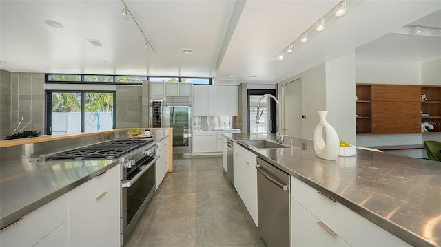 kitchen featuring stainless steel counters, high quality appliances, modern cabinets, and a sink