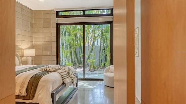 bedroom with concrete floors, access to outside, and tile walls