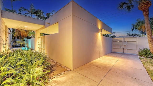 view of side of property featuring fence, stucco siding, and a gate