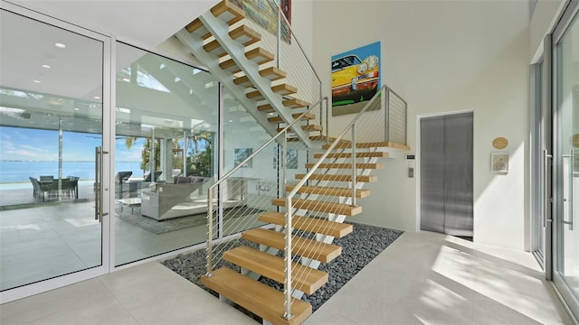 4123 Bay Shore Rd, Sarasota, FL 34234 - stairs with elevator, a towering ceiling, healthy amount of natural light, floor to ceiling windows, and a water view