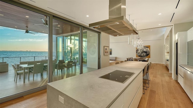 4123 Bay Shore Rd, Sarasota, FL 34234 - kitchen featuring island range hood, white cabinetry, light wood-style flooring, modern cabinets, and a wall of windows