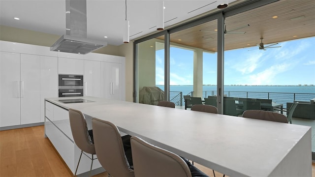 4123 Bay Shore Rd, Sarasota, FL 34234 - kitchen featuring island exhaust hood, modern cabinets, floor to ceiling windows, light wood-style floors, and white cabinetry