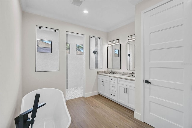 full bathroom with a walk in shower, double vanity, a freestanding tub, a sink, and visible vents