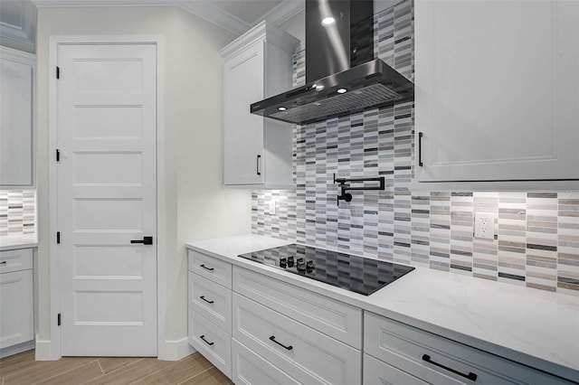 kitchen with wall chimney range hood, backsplash, crown molding, and black electric cooktop