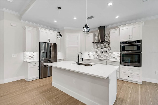 kitchen featuring appliances with stainless steel finishes, wall chimney range hood, a sink, visible vents, and crown molding