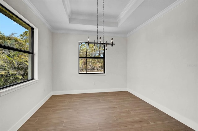 unfurnished dining area with wood finished floors, a tray ceiling, a notable chandelier, and baseboards