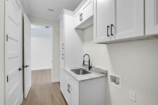 washroom with cabinet space, a sink, light wood-style floors, washer hookup, and visible vents